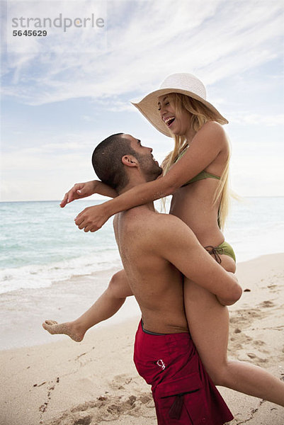 Ein verspieltes junges Paar am Strand