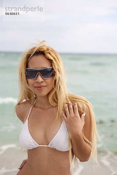 Eine schöne junge Frau im Bikini und Sonnenbrille am Strand