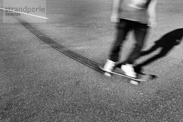 Ein Skateboarder  der Reifenspuren hinterlässt.