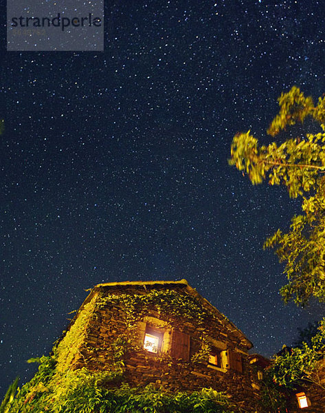 Ein mit Efeu bedecktes Haus unter einem Sternenhimmel.