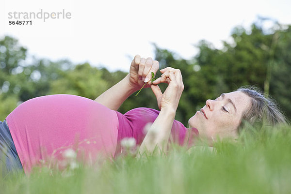 Eine schwangere Frau im Gras liegend  Seitenansicht