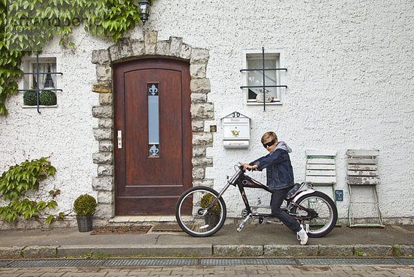 Ein heranwachsender Junge  der auf einem Oldtimer-Motorrad posiert.