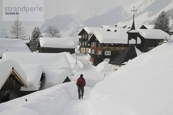 Mann schlendert durch das verschneite Dorf