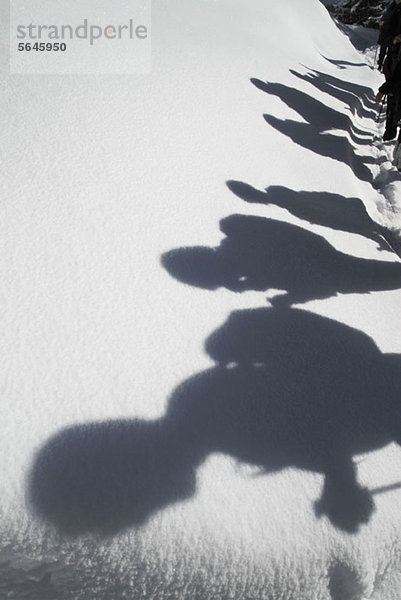 Schatten von Wanderern gegen eine Schneedecke