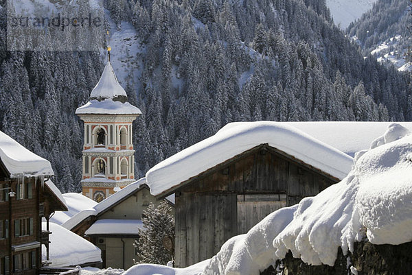 Schneebedecktes Dorf mit Bergwald im Hintergrund