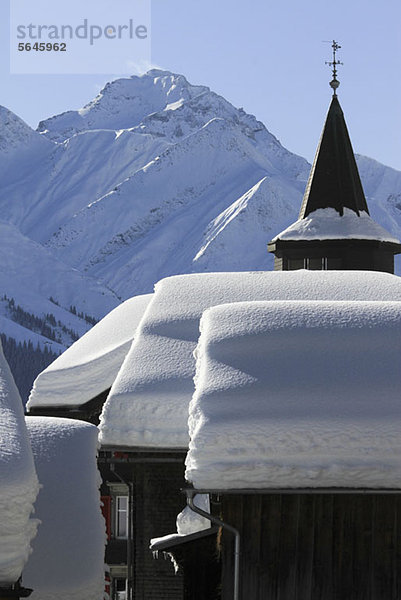 Schneebedeckte Hütten und Bergkette im Hintergrund