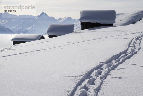 Fußweg zu drei schneebedeckten Blockhütten