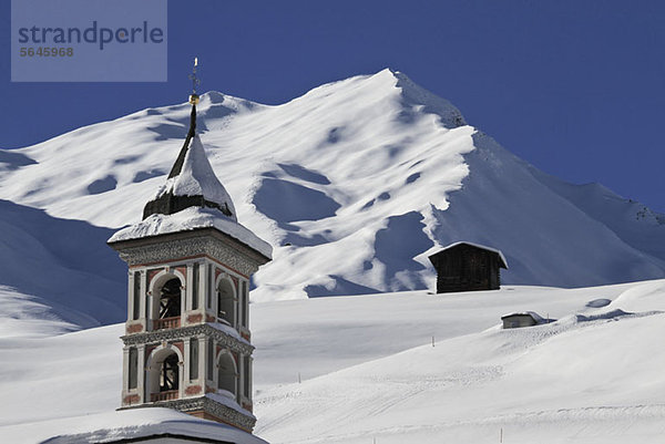 Kirchturm und verschneiter Berg im Hintergrund