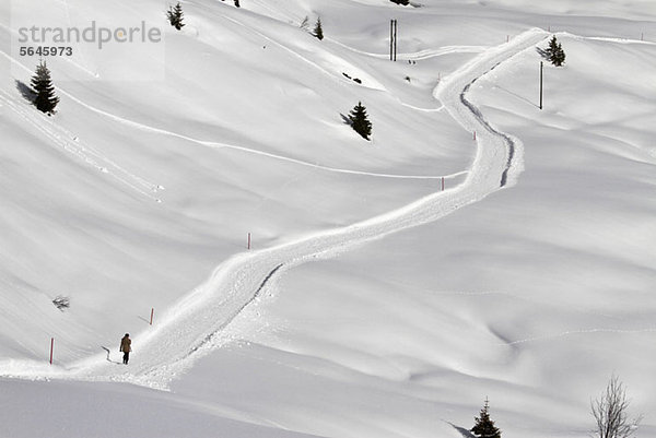 Person  die über einen schneebedeckten Fußweg bergauf geht