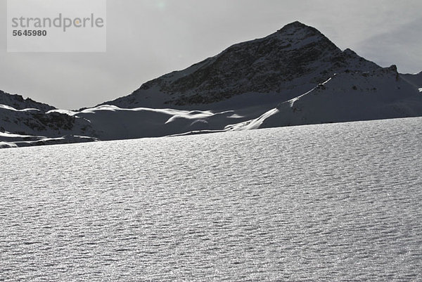 Schneedecke und felsiger Berg im Hintergrund