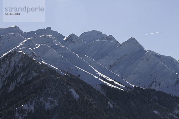 Schneebedeckte Bergkette mit Kondensstreifen im Hintergrund
