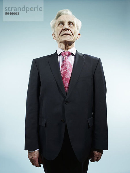 Ein eleganter Senior in Anzug und rosa Paisley-Krawatte.