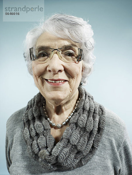 Eine elegante Seniorin lächelt die Kamera an.
