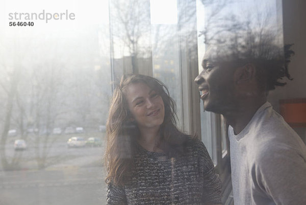 Ein Freund und eine Freundin  die zusammen lachen  durchs Fenster gesehen.