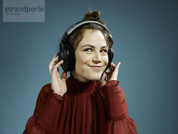 Eine junge hippe Frau mit Kopfhörern und einem Lächeln.
