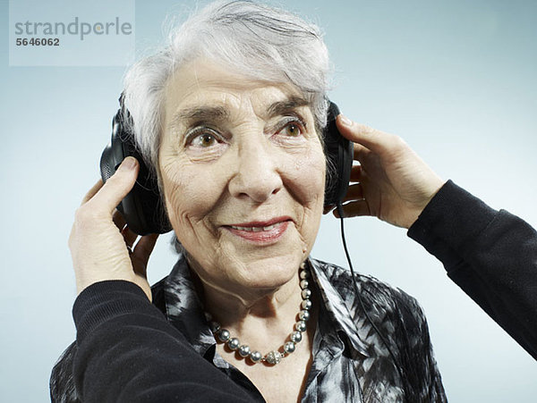 Eine Person  die einer älteren Frau Kopfhörer aufsetzt.