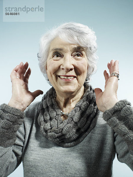 Eine ältere Frau mit überraschend erhobenen Armen