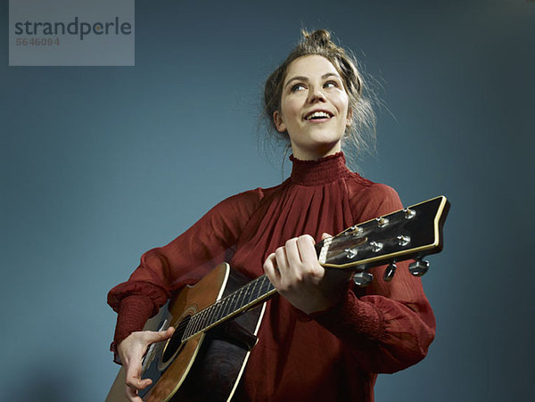 Eine junge Frau spielt eine Akustikgitarre.