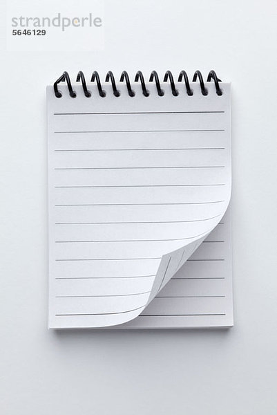 Ein spiralförmiger Notizblock mit liniertem Papier und einer aufgerollten Seitenecke.