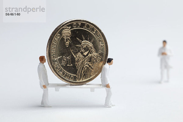Miniatur-Sanitäterfiguren mit einer Euro-Münze auf einer Trage