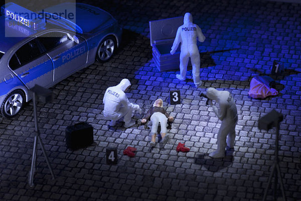 Ein Diorama eines miniaturisierten forensischen Teams  das Beweise an einem Tatort sammelt.