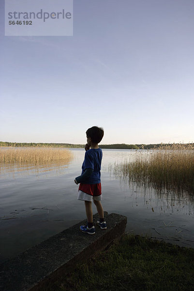 Junge steht am Ufer des Sees