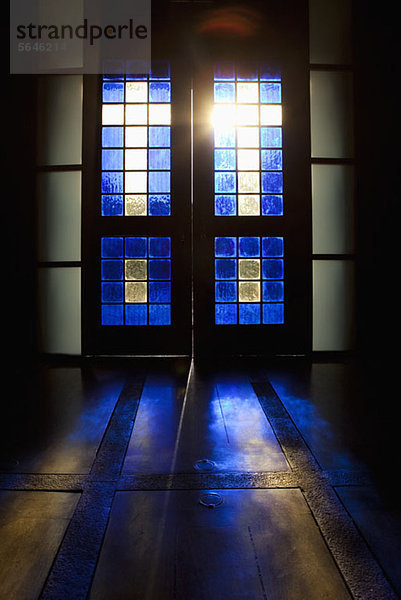Blaue Farbe projiziert auf den Boden durch die Glasmalerei-Tür