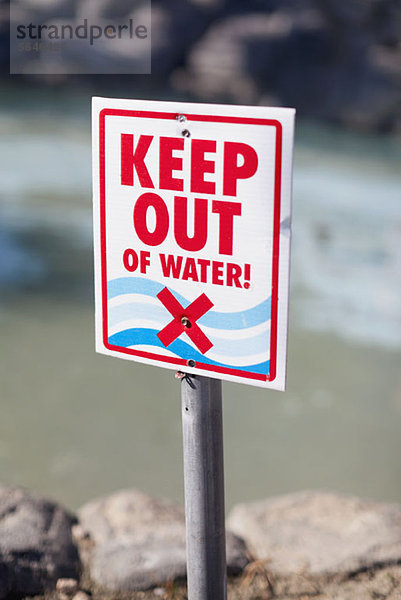 A Keep Out of Water Schild an einem felsigen Strand aufgestellt