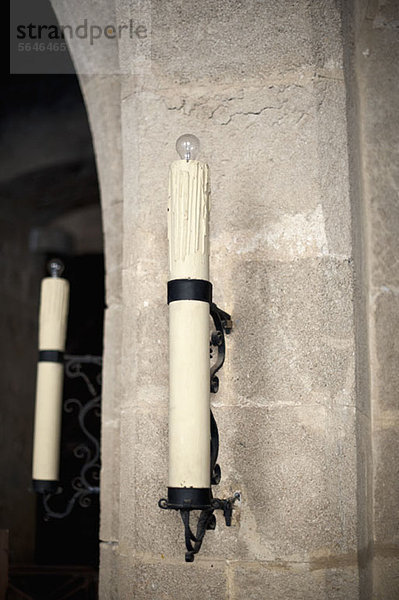 Ein elektrischer Kerzenleuchter  der an einer Zementwand hängt.