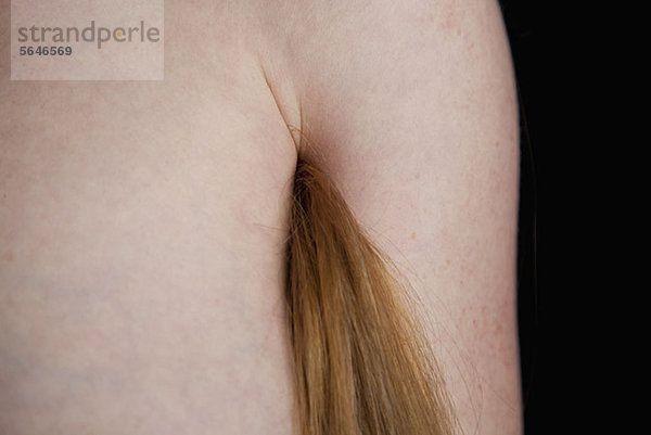 Eine Frau mit langen Haaren aus der Achselhöhle.