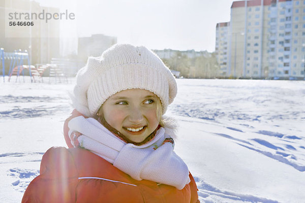 Lächelndes Mädchen in Winterkleidung im verschneiten Stadtpark