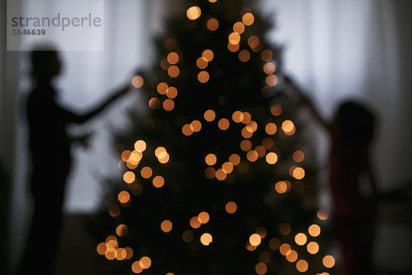 Silhouette von Mutter und Tochter beim Dekorieren eines Weihnachtsbaums