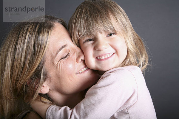 Ein lächelndes junges Mädchen umarmt ihre Mutter  Nahaufnahme