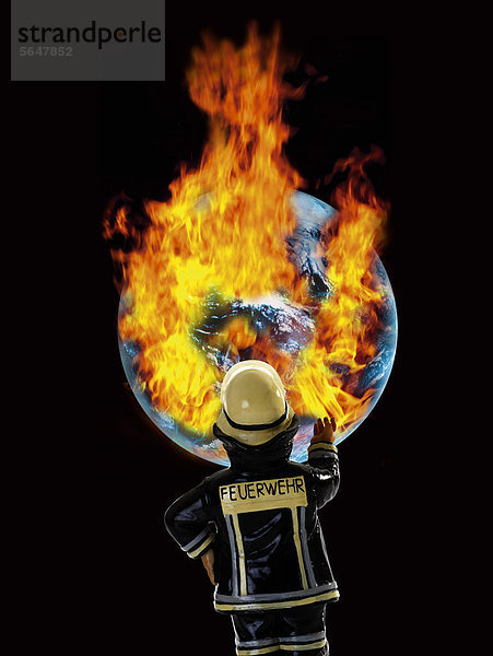 Feuerwehrmann-Figur vor der Erde mit brennendem Feuer  Nahaufnahme