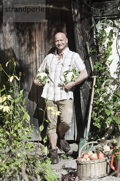 Österreich  Salzburg  Flachau  reifer Mann mit Gemüse  lächelnd  Portrait