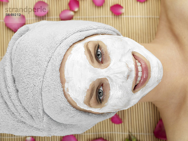 Junge Frau mit Gesichtsmaske im Spa  lächelnd  Portrait