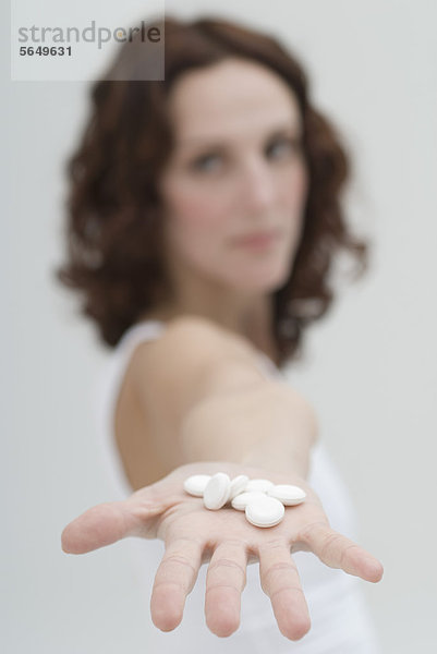 Mittlere erwachsene Frau mit weißen Pillen in der Hand