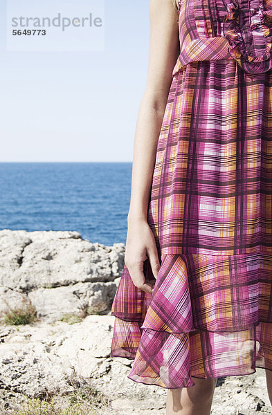 Spanien  Mallorca  Junge Frau stehend mit Meer im Hintergrund