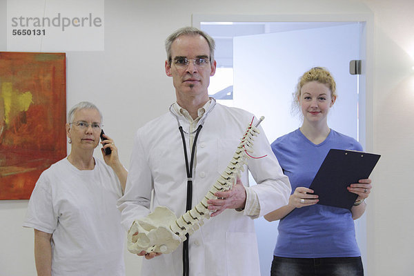 Arzt und sein Team beschreiben Rückenschmerzen an einem Modell