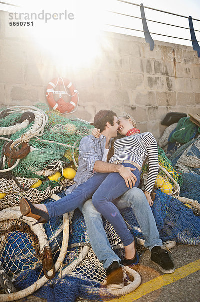 Spanien  Mallorca  Paar am Hafen mit Fischernetzen  lächelnd
