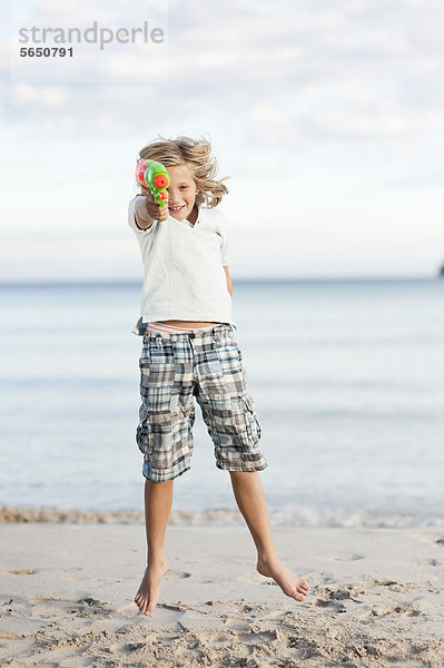 Spanien  Mallorca  Junge mit Wasserpistole am Strand  Portrait