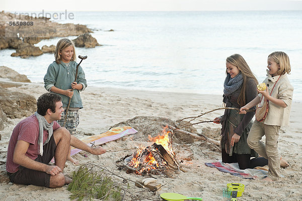 Spanien  Mallorca  Freunde beim Würstchengrillen am Lagerfeuer am Strand