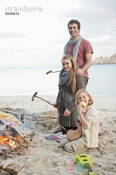 Spanien  Mallorca  Freunde mit Würstchen am Lagerfeuer am Strand