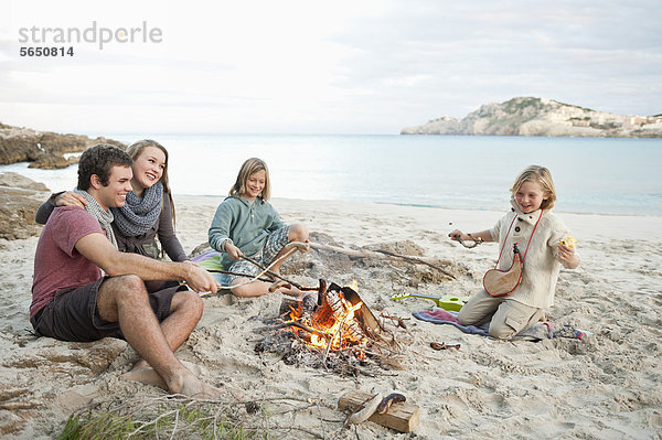 Spanien  Mallorca  Freunde beim Würstchengrillen am Lagerfeuer am Strand