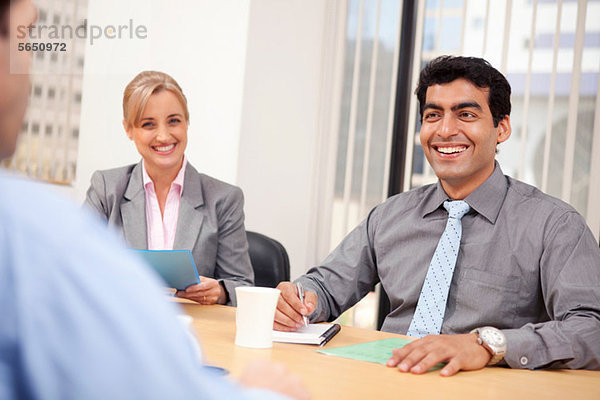 Geschäftsleute lächeln in einer Besprechung