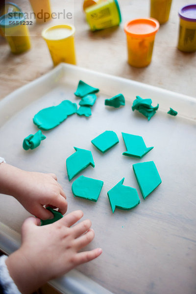 Kind macht Recycling-Symbol aus Spiel-Ton