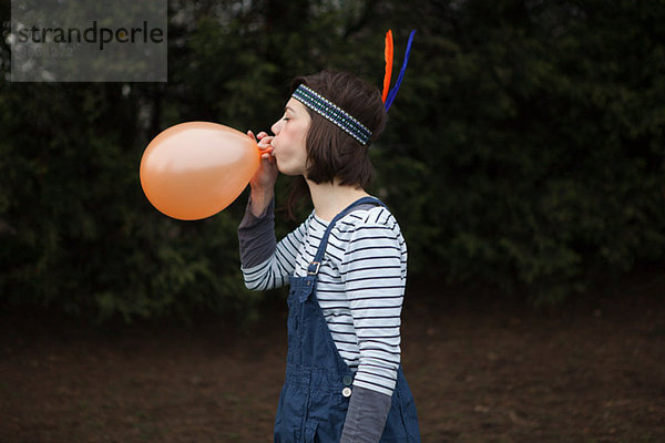 Junge Frau im Kopfschmuck  einen Ballon zu sprengen