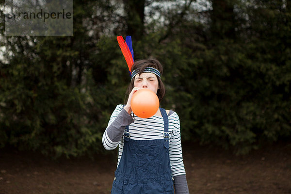 Junge Frau im Kopfschmuck  einen Ballon zu sprengen