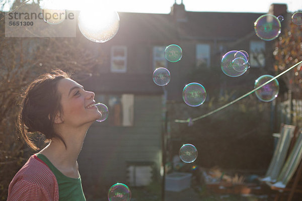 Junge Frau im Freien mit in der Luft schwebenden Blasen