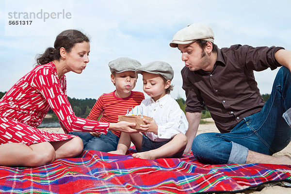 Junge und Familie mit Geburtstagstorte auf Picknickdecke